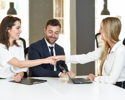 smiling young couple shaking hands with an insuran 5ZTAEJQ
